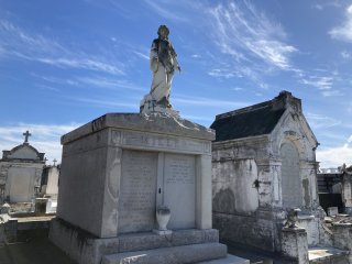 A statue atop a crypt silhouetted against a blue sky.