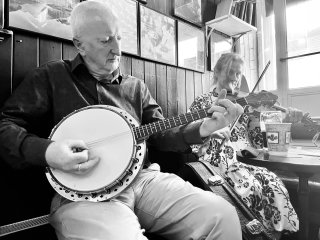 A man playing banjo and a woman playing fiddle.