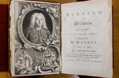 The opening pages of the first printing of Handel's "Messiah" score. An elaborate full-page portrait of Handel, complete with a flowing white wig, is on the left. The title page is on the right.