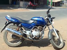 a blue motorcycle is parked on the side of the road in front of a building
