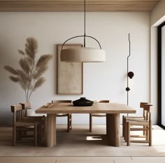 a dining room table and chairs in front of a wall with art hanging above it