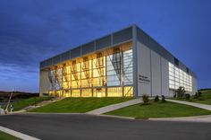 a large building sitting on top of a lush green hillside next to a parking lot