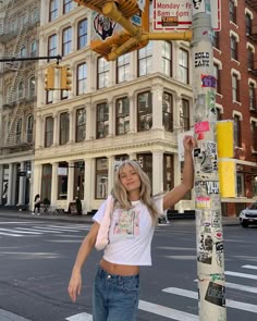 a woman is standing next to a pole with stickers on it in the city