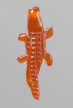 an orange gummy candy shaped like a crocodile on a gray background, with the top part of its body visible