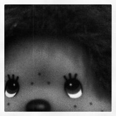 a black and white photo of a child's face with big eyes, looking at the camera