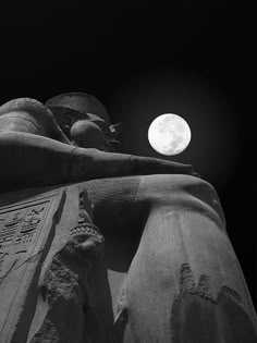the moon shines brightly behind two statues in front of a black and white background