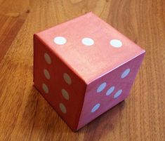 a pink dice sitting on top of a wooden table