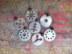 six metal ornaments are hanging on a wooden surface with paint peeling off the wall behind them