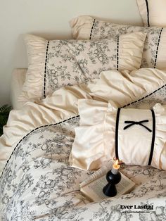 a bed with white and black comforters, pillows and a book on it