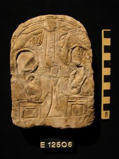 a stone carving with two faces on it and a ruler next to it that shows the scale
