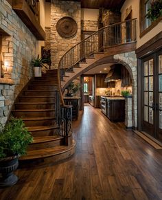 a large open floor plan with wood floors and stone walls, stairs leading up to the kitchen