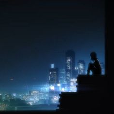 a person sitting on top of a building looking out at the city lights in the distance