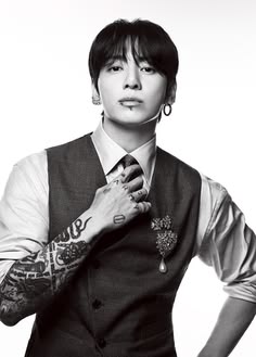 a man with tattoos is adjusting his tie