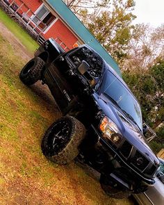 a black truck parked in front of a red house