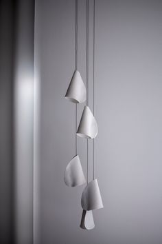 three white lamps hanging from the ceiling next to each other in front of a gray wall