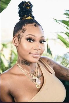 a woman with tattoos on her arm and neck posing for a photo in front of some trees