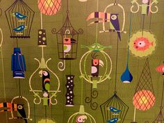 colorful birds and cages hanging from hooks on a green wallpapered background with blue, red, orange, yellow, and pink colors