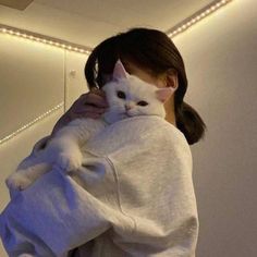 a woman holding a white cat in her arms