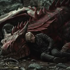a man laying on the ground next to a dragon