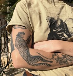 a woman with her arms crossed and tattoos on her chest is standing in front of an iron fence