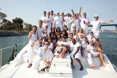 a group of people posing for a photo on a boat in the water with their arms up