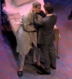 two people standing next to each other near a bed