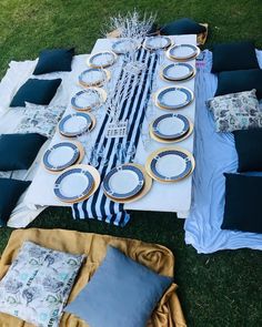 a table set up with blue and white plates, napkins and place settings on it
