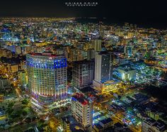 an aerial view of a city at night with buildings lit up in blue and yellow