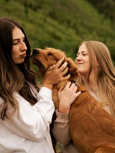 two women are holding a dog in their hands