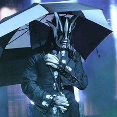 a man in black coat holding an umbrella with skulls on it and skull head decorations