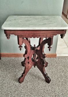 a wooden table with marble top sitting on carpeted floor