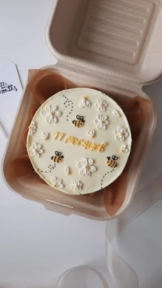 a cake in a box with the word happy on it and some bees around it