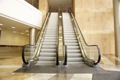an escalator in a large building with stairs leading up to the second floor