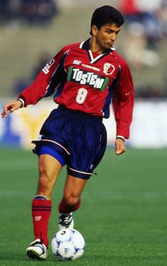 a young man kicking a soccer ball on top of a field