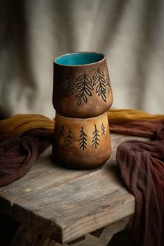 two brown bowls sitting on top of a wooden table next to a red towel and blanket