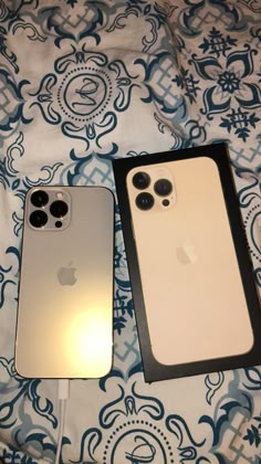 two iphones sitting on top of a bed next to each other in their packaging