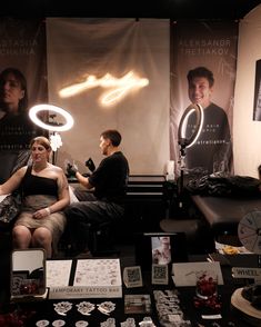 a man and woman sitting in front of a mirror with lights on it's sides