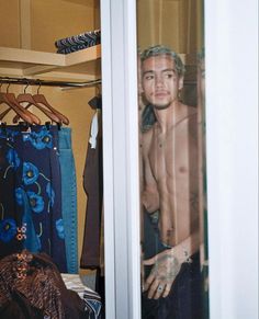 a shirtless man standing in front of a closet