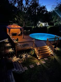 an above ground pool lit up at night with deck lighting and steps leading to it