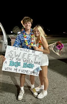two people standing next to each other holding a sign