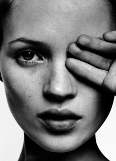 a black and white photo of a woman covering her eyes