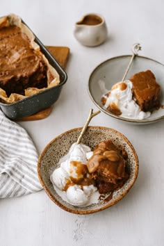 two bowls filled with dessert and ice cream on top of a white table next to other dishes