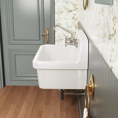 a white sink sitting on top of a wooden floor next to a wall mounted faucet