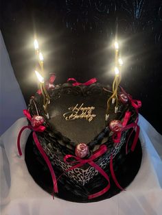 a heart shaped cake with two lit candles on it and some ribbons around the edges