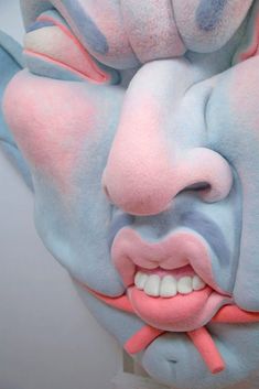 a man with his face painted blue and pink to look like he is holding a toothbrush in his mouth