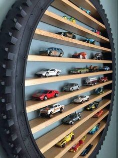 there are many toy cars on the shelves in this wall display case that is made out of tire rims