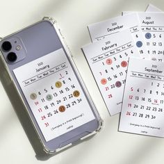 a cell phone sitting on top of a table next to calendars