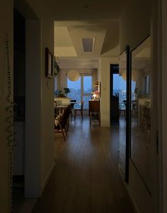 an empty hallway leading to a living room and dining room with large windows overlooking the city