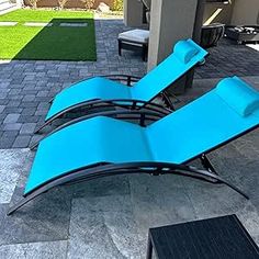 two blue lounge chairs sitting on top of a patio
