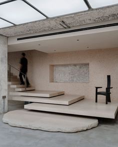 a person walking up some stairs in a room with concrete walls and flooring on the ground